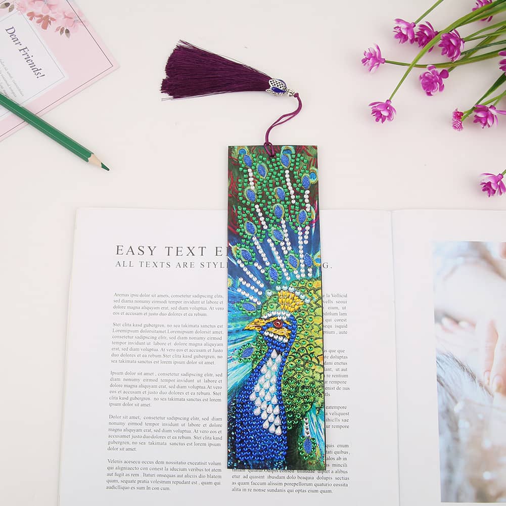 Diamond Painting Bookmark with Peacock Design on Open Book with Flowers and Pencil.