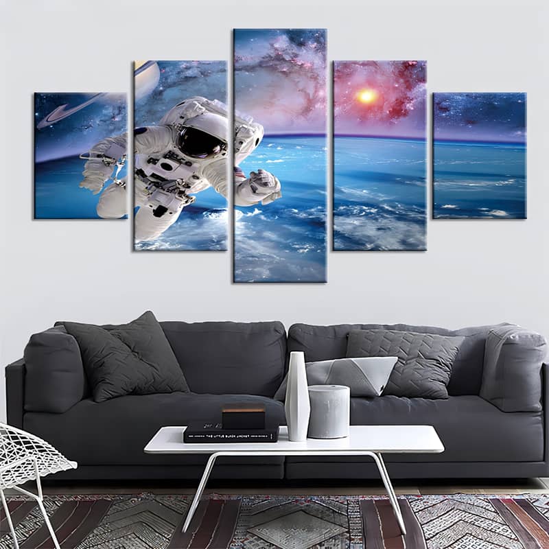 Diamond painting wall art set of 5 featuring an astronaut in space above Earth, displayed above a modern living room sofa.