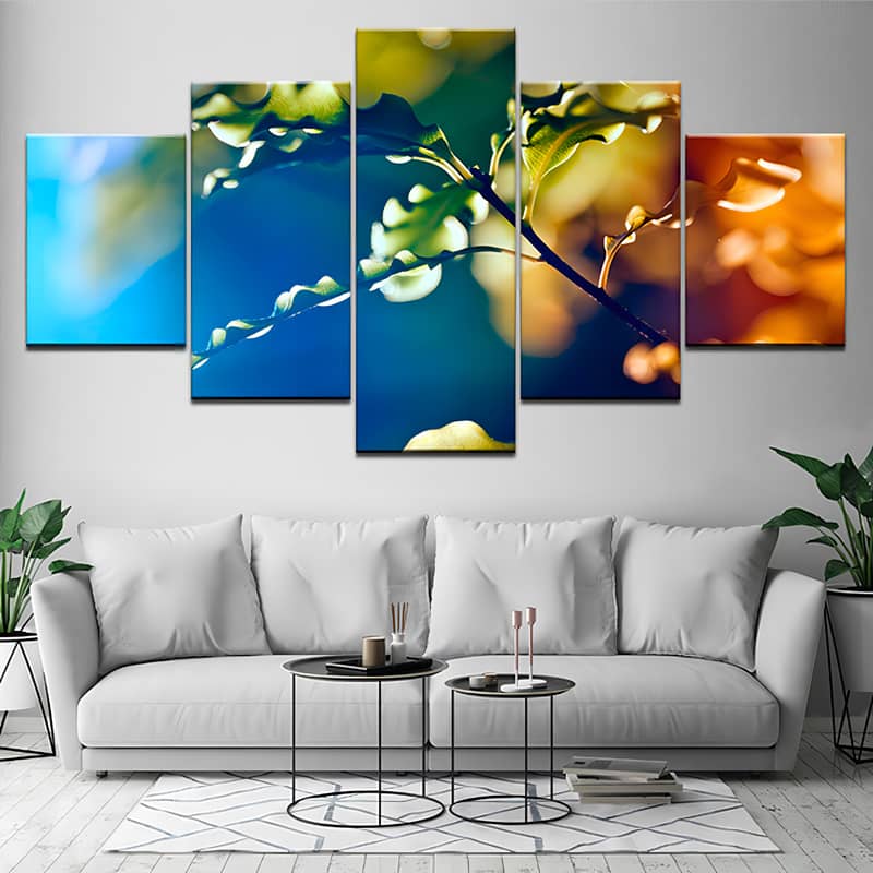 Diamond painting of a tree branch in a colorful background, split into 5 pieces, displayed above a modern white couch in a living room