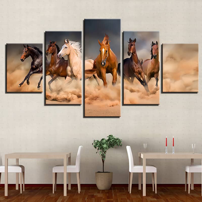 Diamond painting wall art of 5 galloping horses in the sand, displayed above dining tables and chairs.