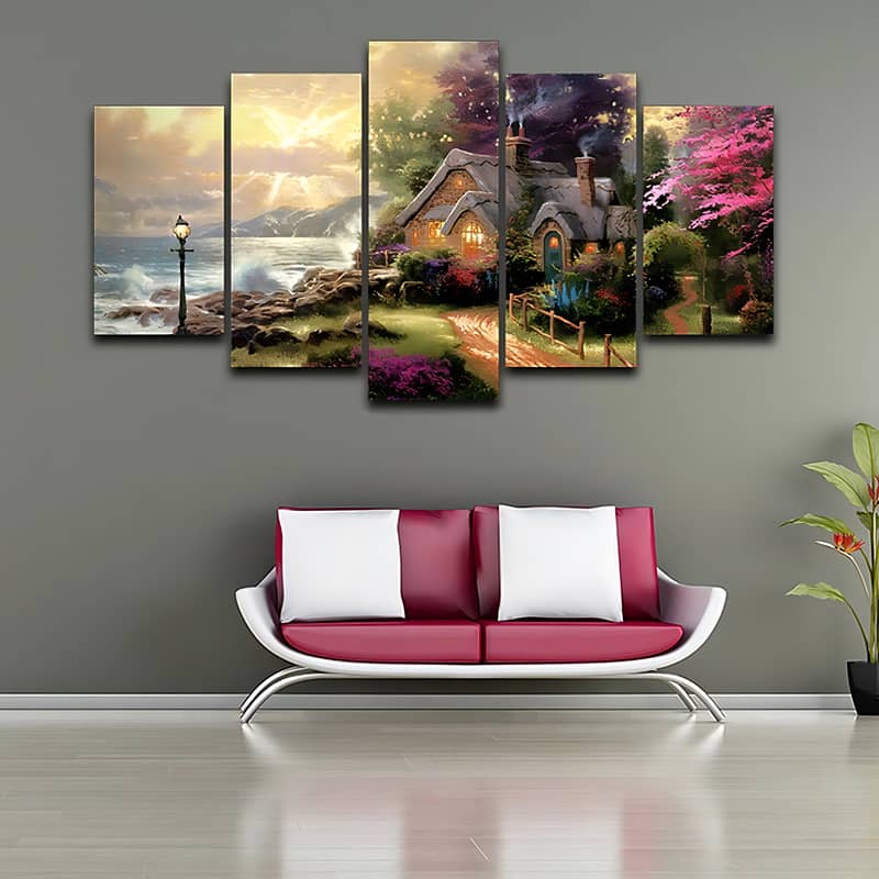 Diamond Painting 5 parts featuring an idyllic cottage at the edge of the forest and sea coast, displayed above a modern sofa.