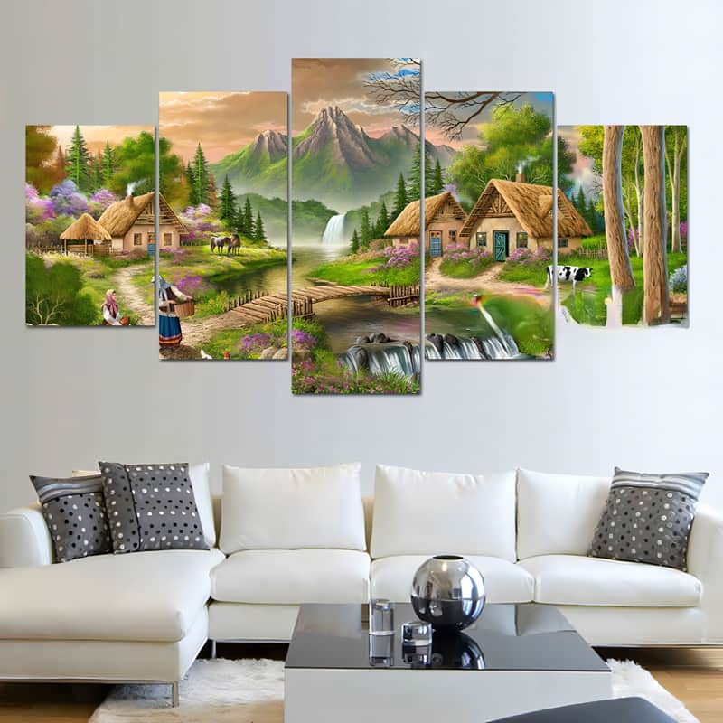 Diamond painting of a small mountain village at the edge of a forest, displayed in five pieces above a modern white sofa.
