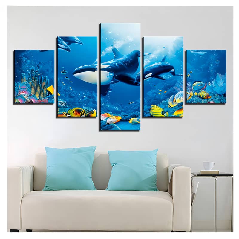 Diamond painting of orca whale family in ocean, 5-piece wall art set with colorful fish, displayed above a white couch with blue pillows