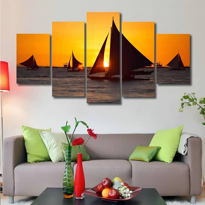 Diamond painting set of 5 pieces featuring sailing ships in a beautiful sunset over an ocean, displayed above a modern living room sofa.