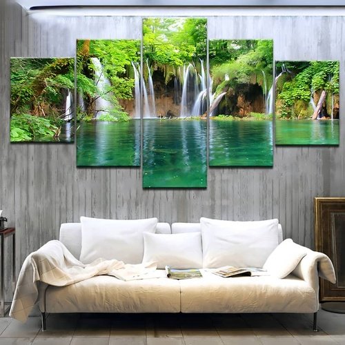 Diamond painting of a serene waterfall lagoon in a lush forest, displayed in five parts above a white couch in a modern living room.
